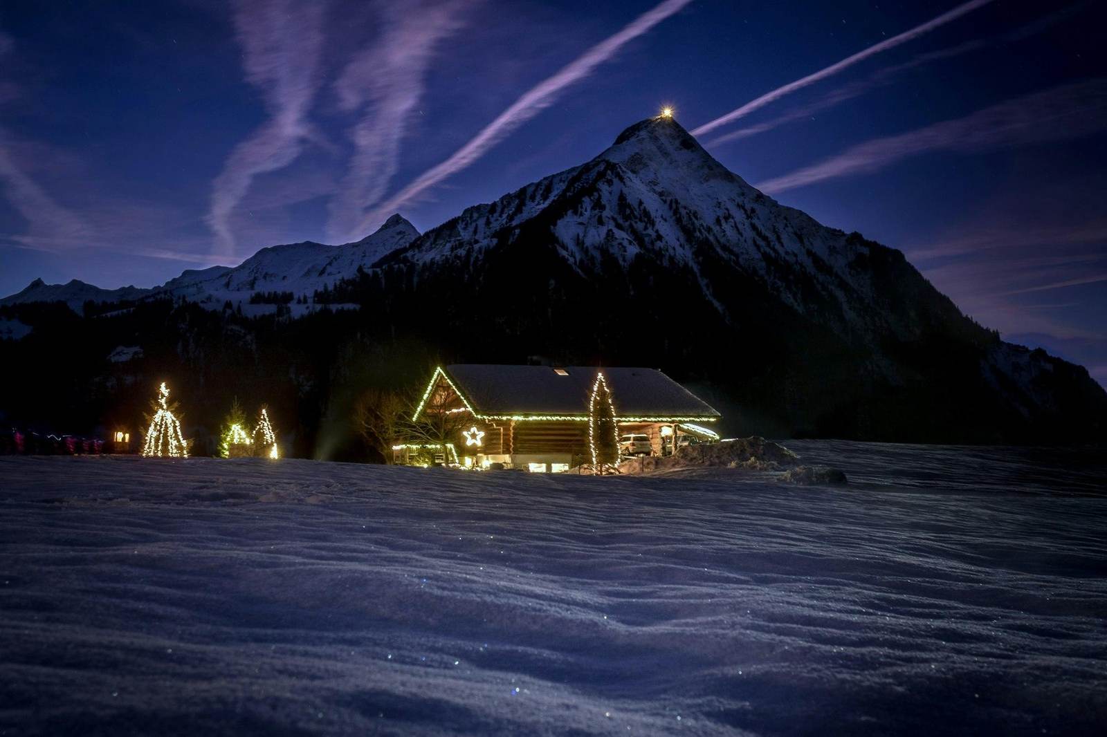 Beleuchtetes Chalet unter einem Gipfel bei Nacht