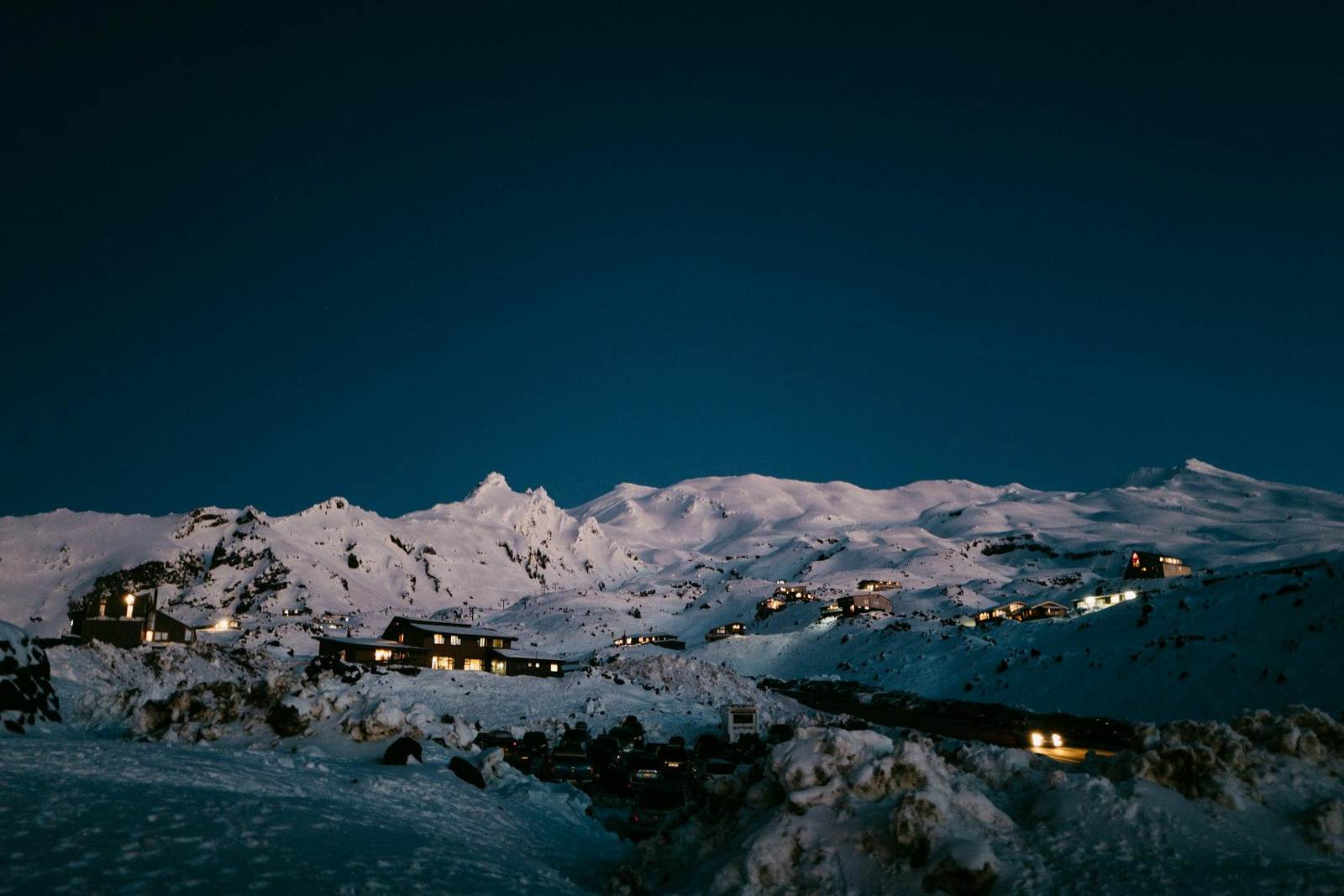 Beleuchtete Häuser auf einem verschneiten Bergrücken in der Nacht