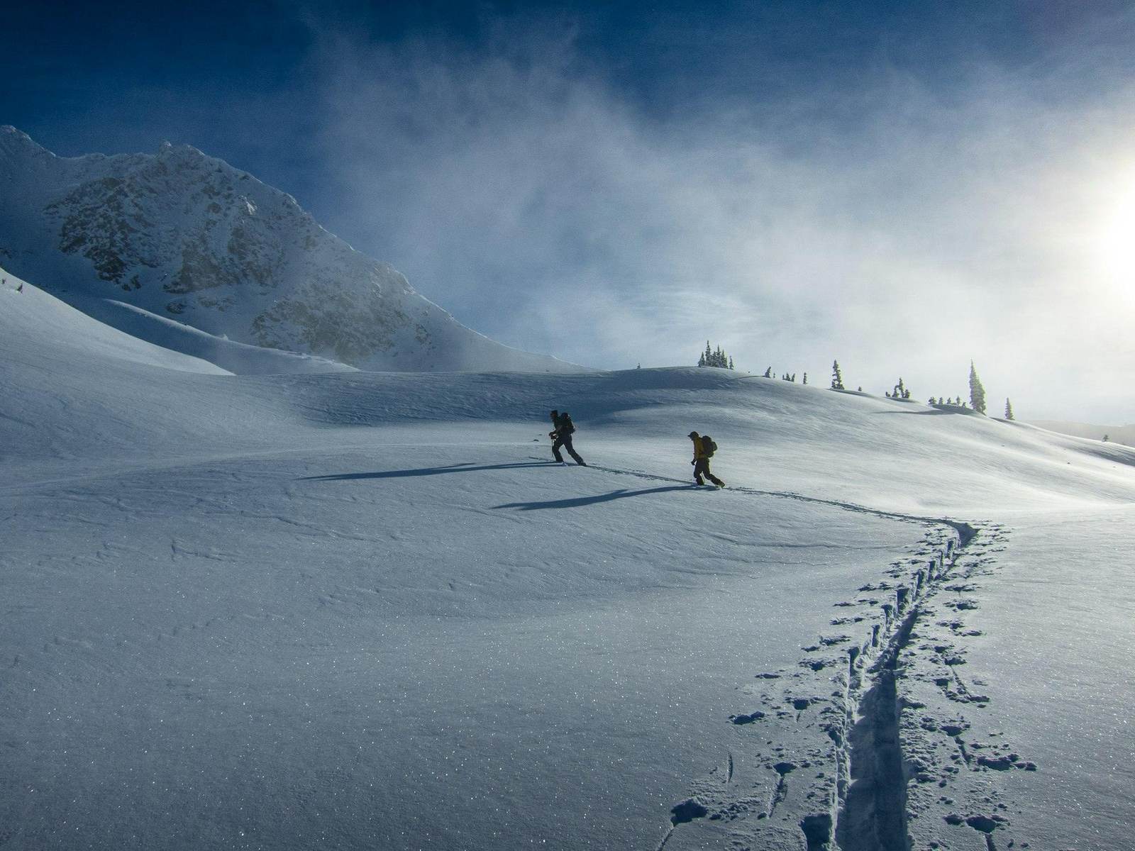 Zwei Tourengeher steigen in weiter Schneelandschaft auf