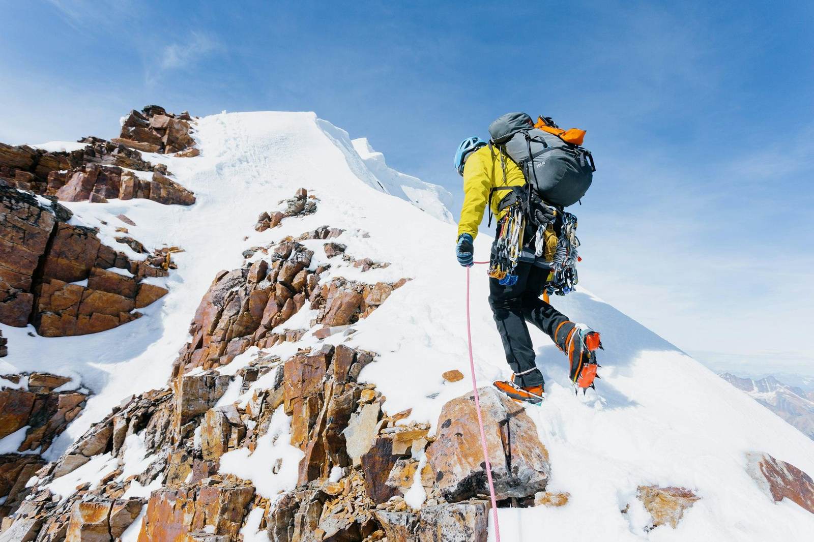 Ein Bergsteiger klettert über verschneite Felsen