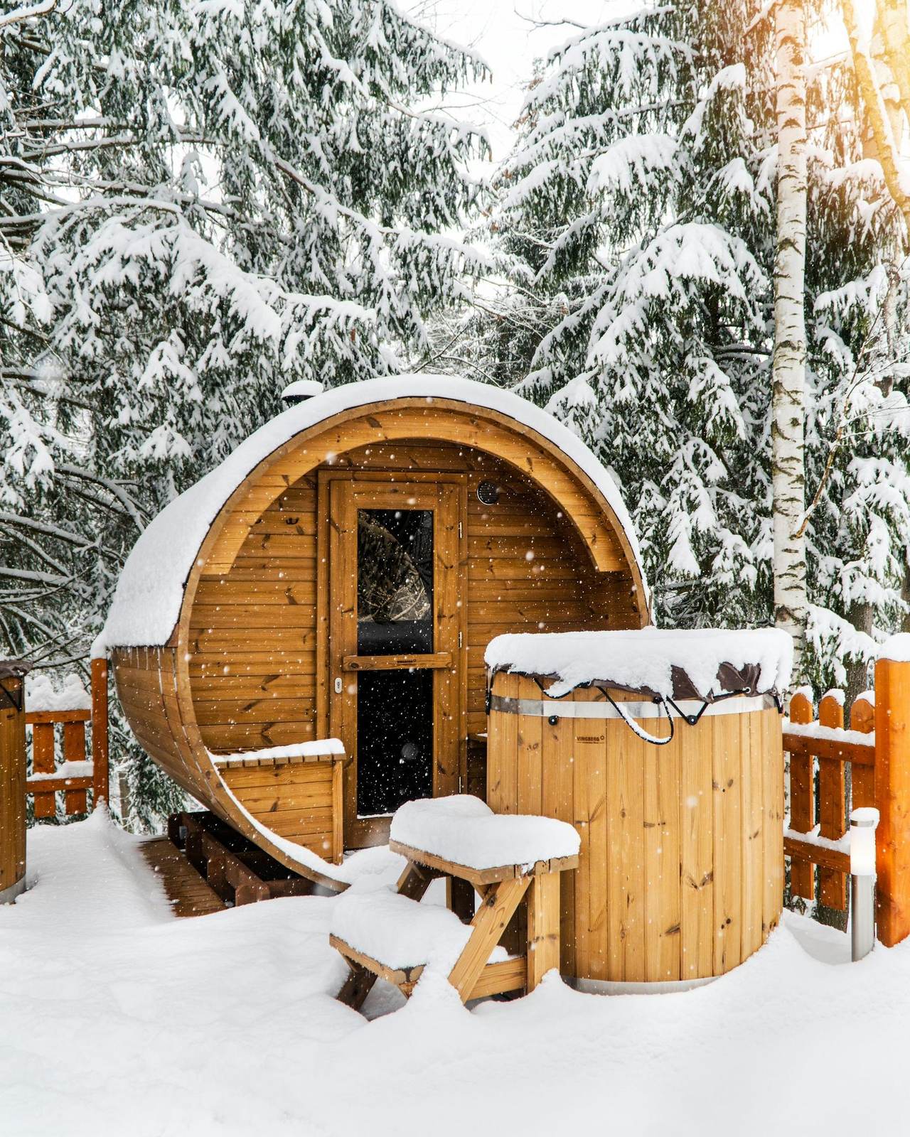Fasssauna und Hot Tub im verschneiten Wald